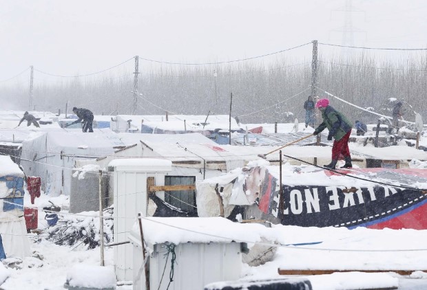 Syrian refugees remove snow from tents during snow fall outside tents at a makeshift settlement in Bar Elias
